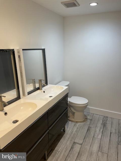 bathroom with hardwood / wood-style floors, vanity, and toilet