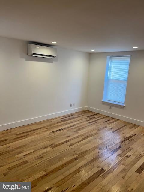 spare room featuring light hardwood / wood-style flooring and a wall unit AC