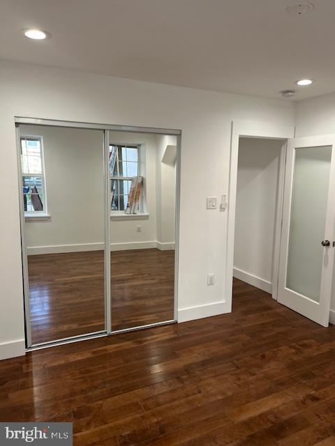 unfurnished bedroom with a closet and dark wood-type flooring