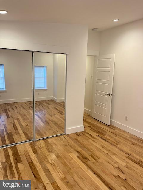 unfurnished bedroom with light wood-type flooring and a closet