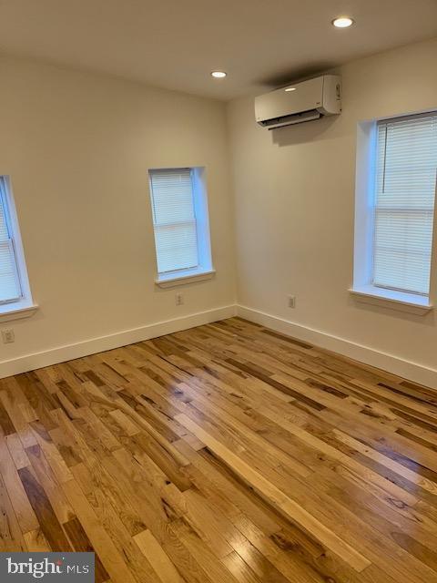 spare room with a wall mounted air conditioner and light hardwood / wood-style flooring