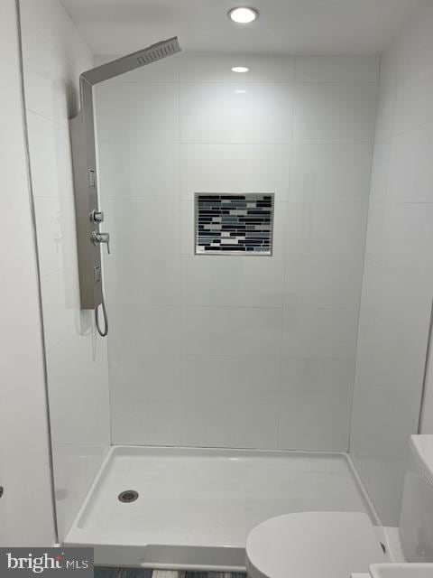 bathroom with a tile shower and toilet