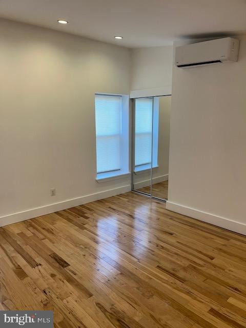 empty room with a wall mounted air conditioner and light wood-type flooring