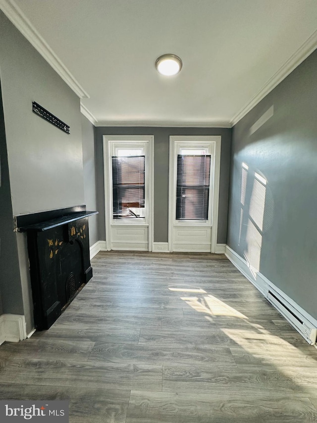 unfurnished living room featuring wood-type flooring, ornamental molding, and baseboard heating