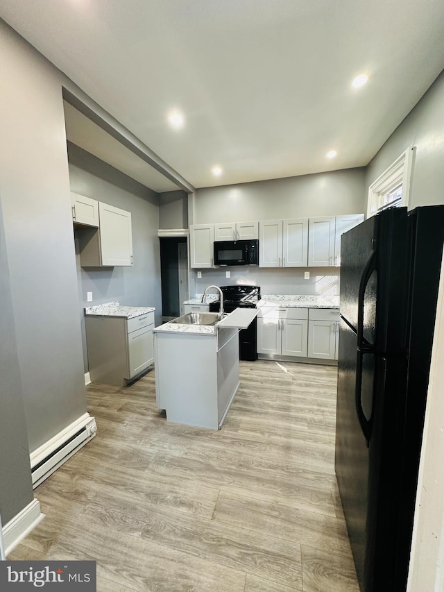 kitchen with black appliances, white cabinets, a kitchen island with sink, and a baseboard radiator