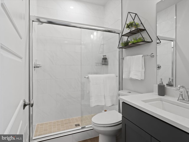 bathroom featuring vanity, toilet, and a shower with shower door