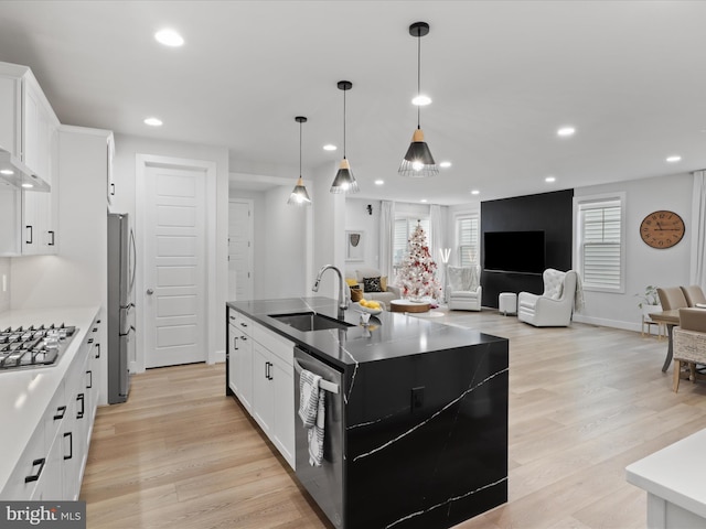 kitchen featuring sink, stainless steel appliances, an island with sink, white cabinets, and light wood-type flooring