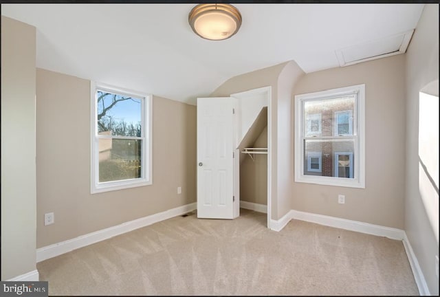 unfurnished bedroom featuring light colored carpet, lofted ceiling, and a closet