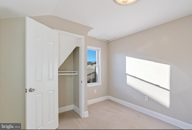 unfurnished bedroom with light colored carpet, lofted ceiling, and a closet