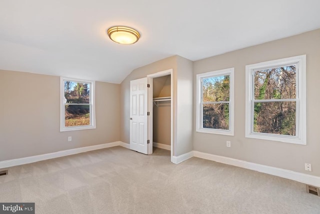 unfurnished bedroom featuring a closet, light colored carpet, and lofted ceiling