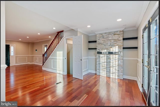 unfurnished living room with crown molding, french doors, and wood-type flooring