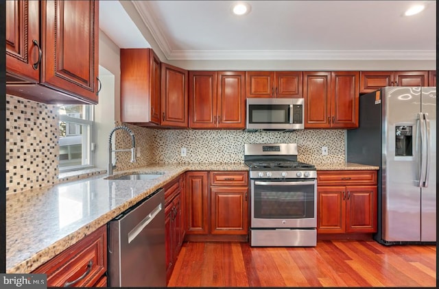 kitchen with appliances with stainless steel finishes, light wood-type flooring, and backsplash