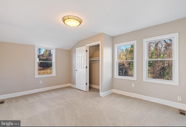 unfurnished bedroom with light carpet, vaulted ceiling, and a closet