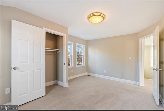 unfurnished bedroom with light carpet and a closet