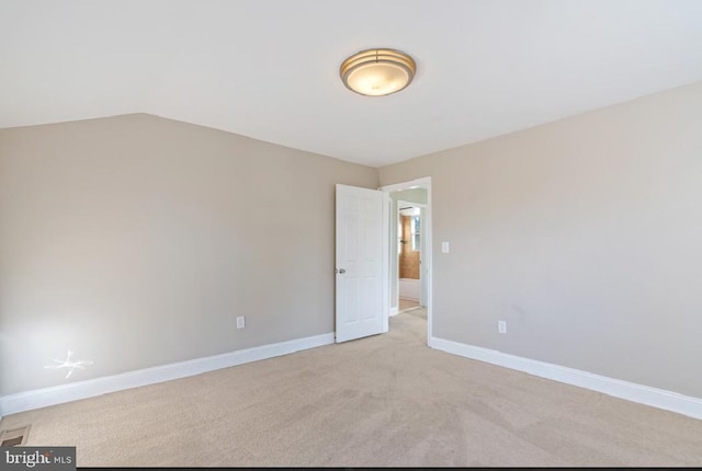 carpeted spare room featuring vaulted ceiling