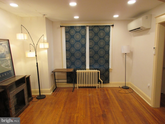 unfurnished room featuring radiator, a wall mounted air conditioner, and hardwood / wood-style flooring