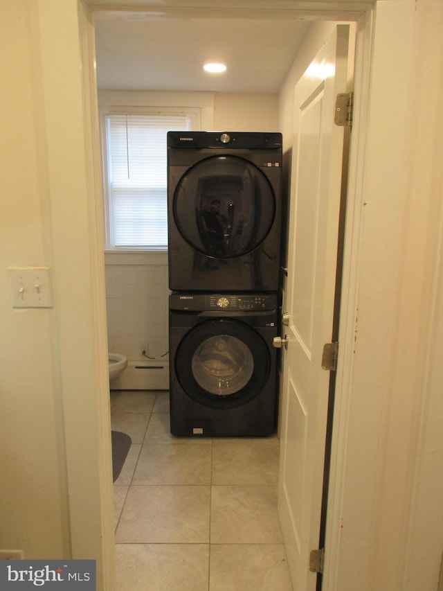 laundry area featuring light tile patterned flooring and stacked washing maching and dryer