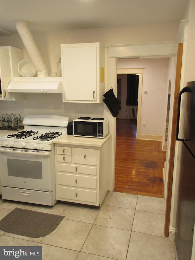 kitchen featuring white cabinets, ventilation hood, radiator heating unit, light hardwood / wood-style flooring, and white range with gas stovetop