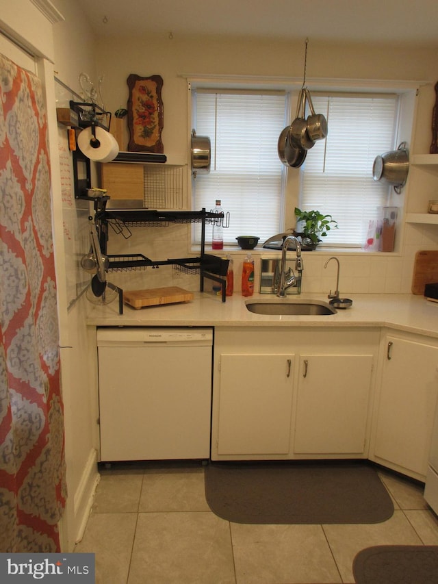 kitchen with dishwasher, light tile patterned flooring, white cabinetry, and sink