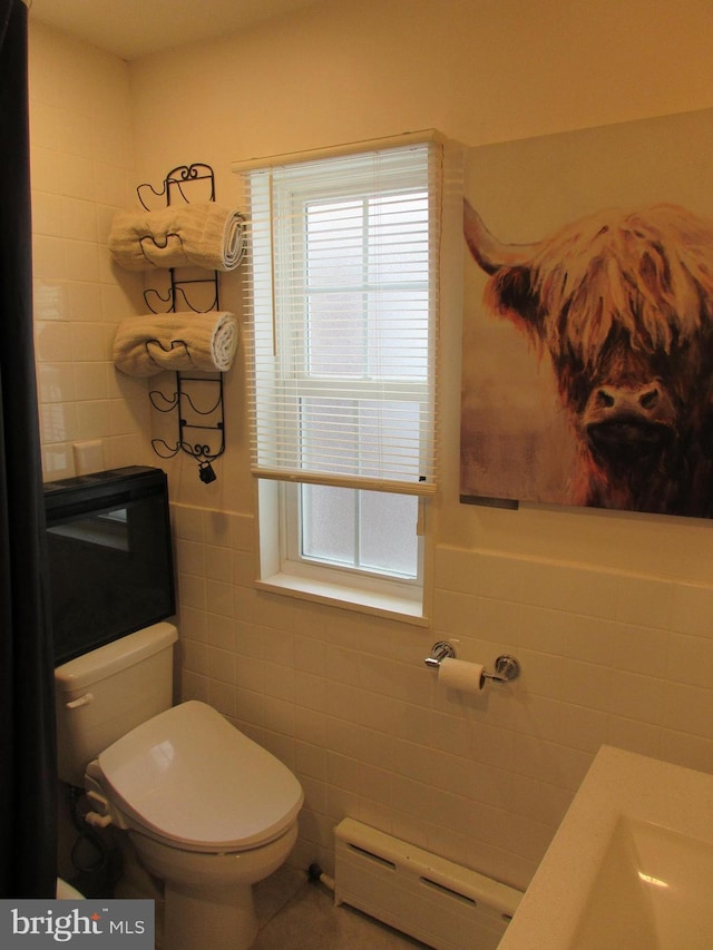 bathroom with a baseboard radiator, tile walls, and toilet