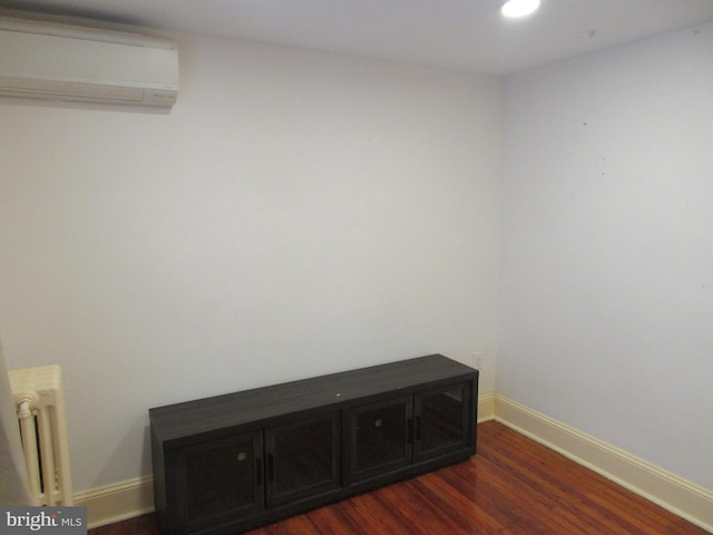 details featuring a wall unit AC, radiator, and hardwood / wood-style floors