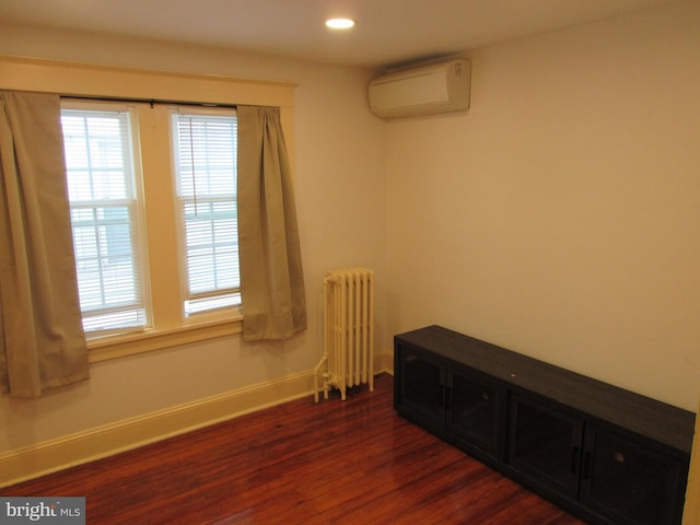 spare room featuring radiator heating unit, dark hardwood / wood-style flooring, and a wall unit AC