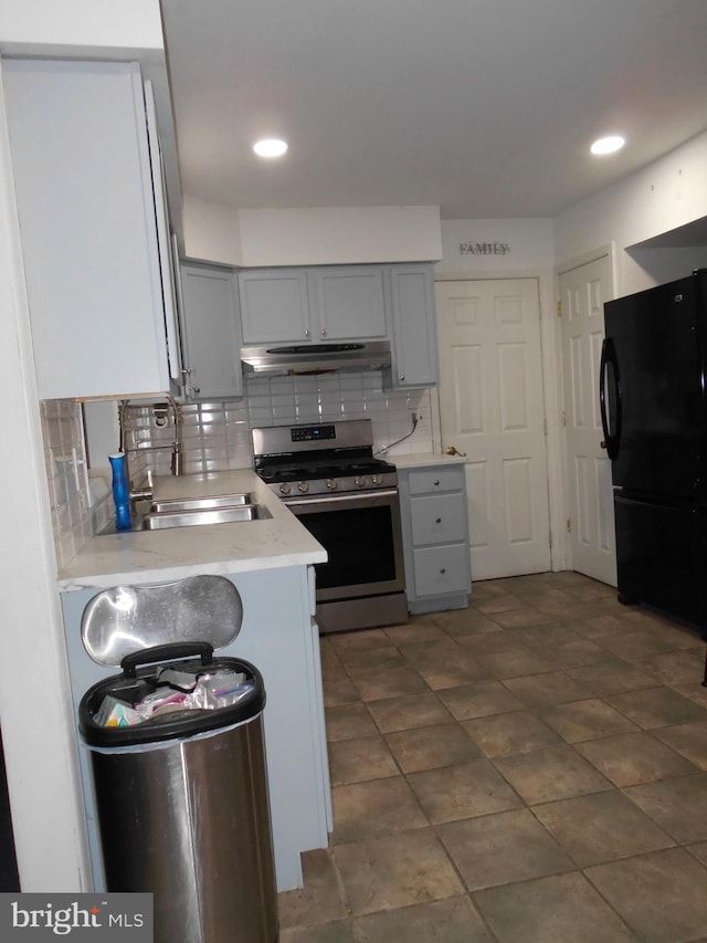 kitchen featuring sink, gray cabinetry, tasteful backsplash, stainless steel gas stove, and black refrigerator