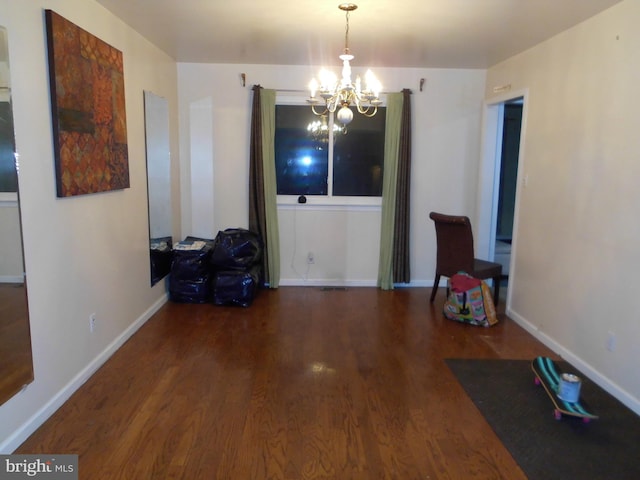 dining room with dark wood-type flooring and a notable chandelier