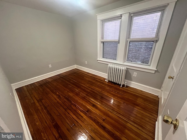 empty room with dark hardwood / wood-style floors and radiator