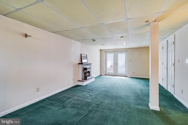 basement with french doors, a paneled ceiling, and dark carpet