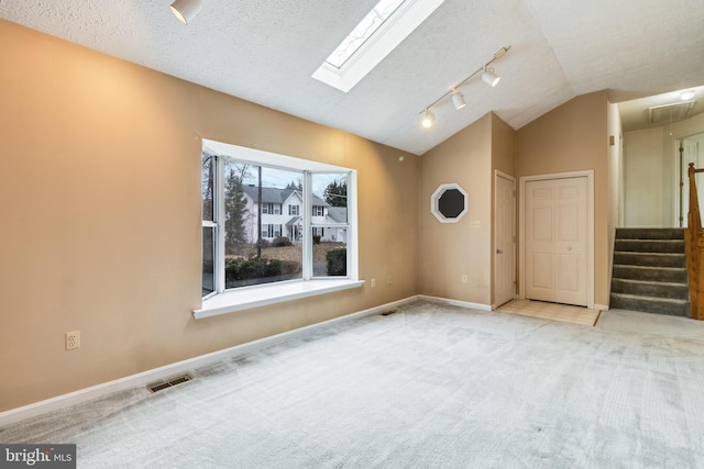 carpeted empty room with rail lighting, lofted ceiling, and a textured ceiling