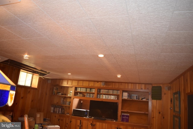 unfurnished living room with built in shelves and wood walls