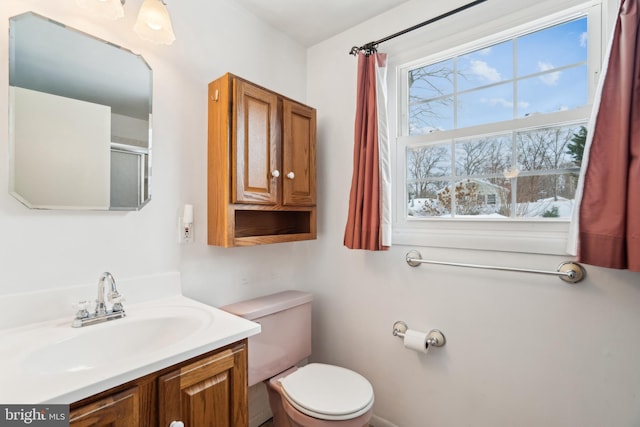 bathroom with walk in shower, vanity, and toilet