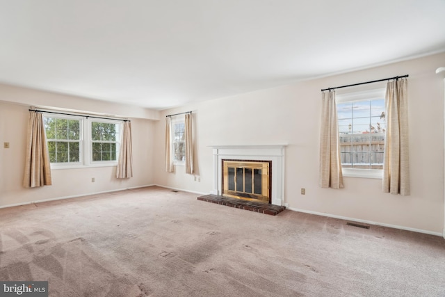 unfurnished living room featuring carpet, a fireplace, and a wealth of natural light