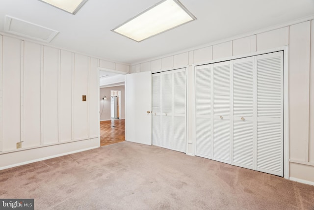 unfurnished bedroom with light colored carpet and two closets