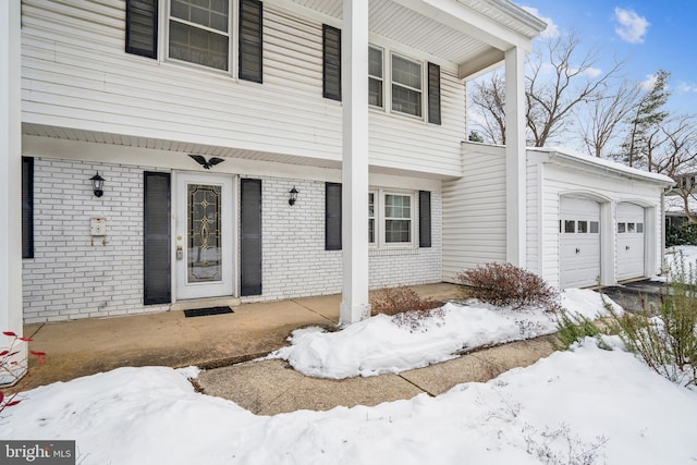 snow covered property entrance featuring a garage