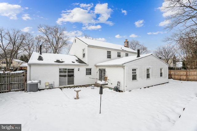 snow covered rear of property featuring central AC