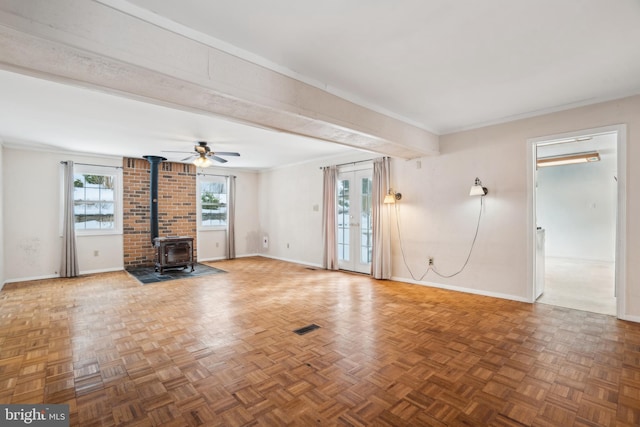 unfurnished living room with a wood stove, ceiling fan, french doors, parquet flooring, and crown molding