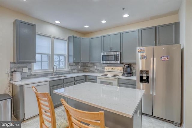 kitchen with light stone countertops, sink, a center island, light tile patterned floors, and appliances with stainless steel finishes