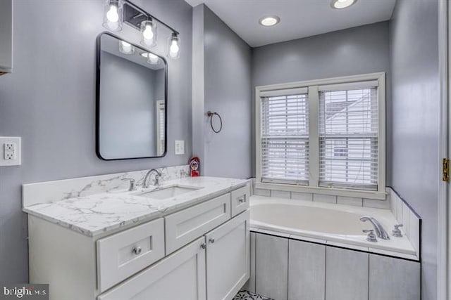 bathroom featuring tiled bath and vanity