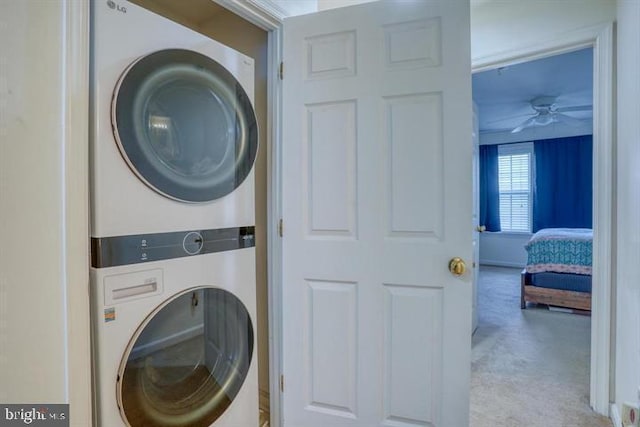 laundry area featuring ceiling fan, light colored carpet, and stacked washing maching and dryer