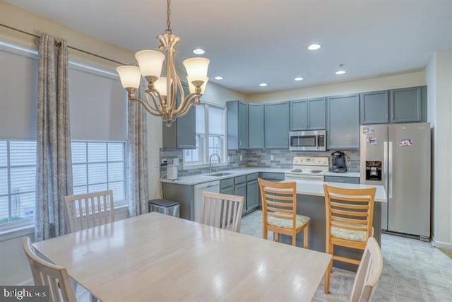 kitchen featuring sink, an inviting chandelier, plenty of natural light, pendant lighting, and appliances with stainless steel finishes