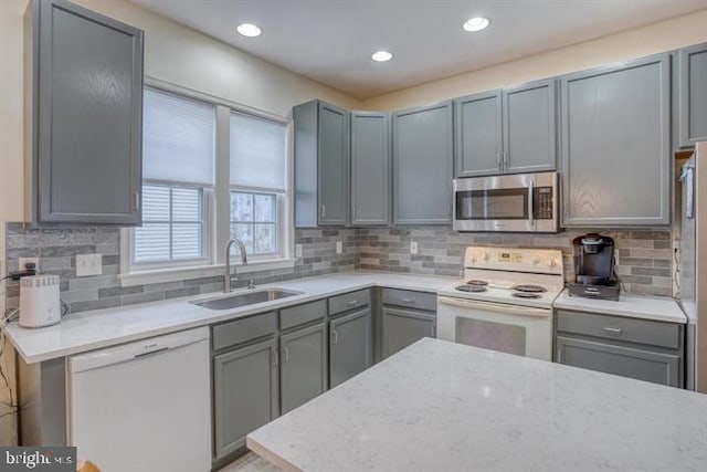 kitchen with white appliances, gray cabinetry, and sink