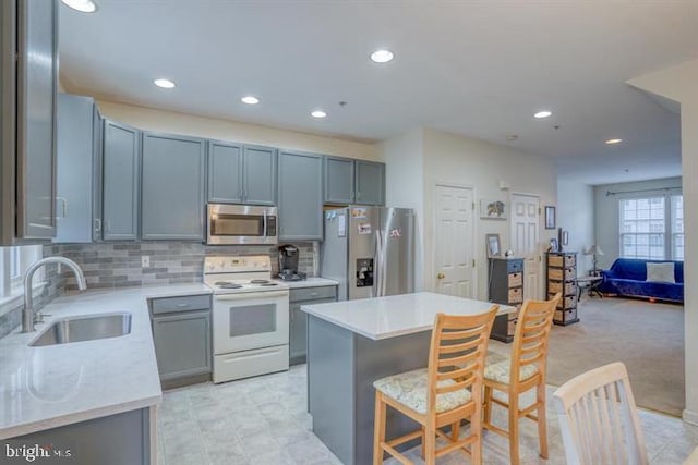 kitchen featuring a kitchen bar, stainless steel appliances, light colored carpet, sink, and a kitchen island