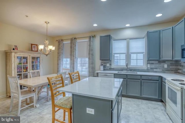 kitchen with hanging light fixtures, electric stove, sink, and a wealth of natural light