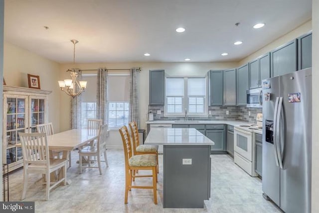 kitchen with sink, decorative light fixtures, a notable chandelier, a kitchen island, and stainless steel appliances