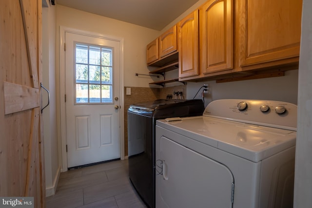 laundry area with washing machine and clothes dryer and cabinets