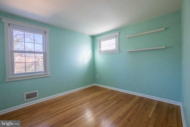 spare room featuring a healthy amount of sunlight and hardwood / wood-style flooring