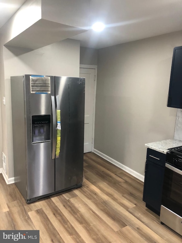 kitchen with light stone countertops, light hardwood / wood-style floors, and appliances with stainless steel finishes