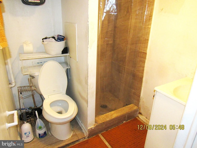 bathroom with tiled shower, vanity, and toilet